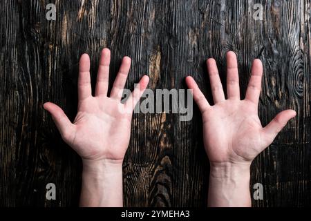 common human hands on dark wooden table with palms up Stock Photo