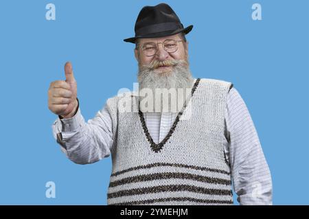 Handsome senior man shows thumb up. Isolated on blue Stock Photo