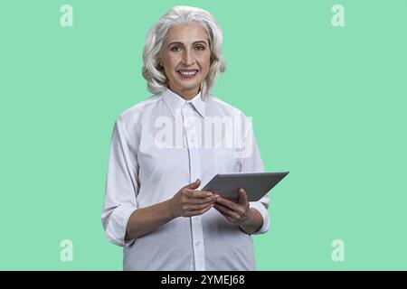 Smiling mature woman using tablet pc on color background. People and modern technology concept Stock Photo