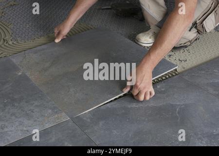 Close-up of tiler laying the floor tiles Stock Photo