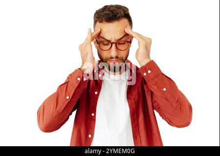 Caucasian or arabian man with glasses pressing his fingers to his temples, showing concentration or mental effort, dressed casually in a red shirt and white t-shirt, stand on isolated white background Stock Photo