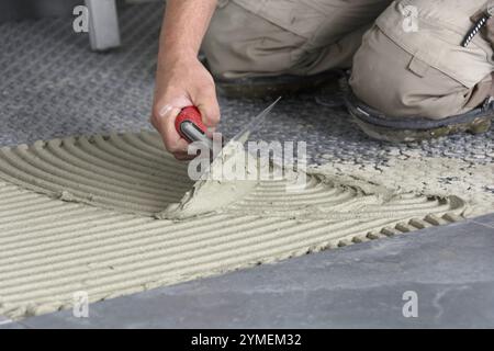 Close-up by hand with notched trowel when applying tile adhesive Stock Photo