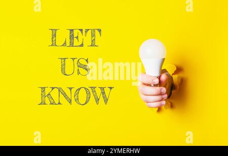 Person holding a light bulb with the words let us know written underneath Stock Photo