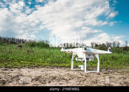 white quadrocopter standing on the ground with spring field and blu sky on the background Stock Photo