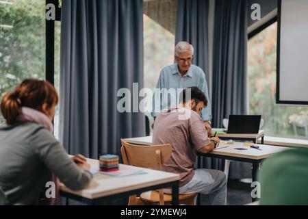Students engaged in a classroom setting with elderly professor Stock Photo