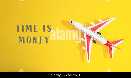 Toy airplane is on a yellow background with the words Time is money written below it Stock Photo