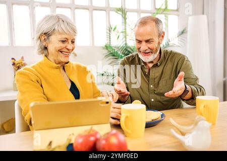 Senior couple having breakfast and using tablet at home Stock Photo