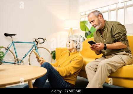 Senior couple using mobile phones and digital tablet at home Stock Photo