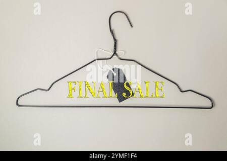 Clothes hanger with a tag that says Final Sale on it. The hanger is hanging on a wall Stock Photo