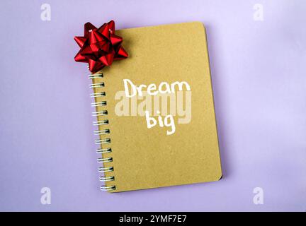 Spiral bound notebook with a red bow on top and the words dream big written in white Stock Photo