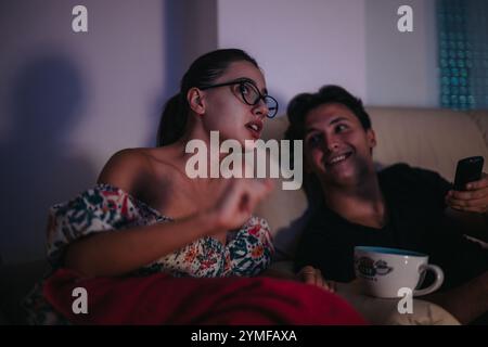 Young couple enjoying a cozy evening watching TV together Stock Photo