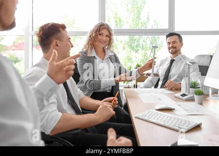 Colleagues with wind turbine models at table during business meeting in office. Green energy concept Stock Photo