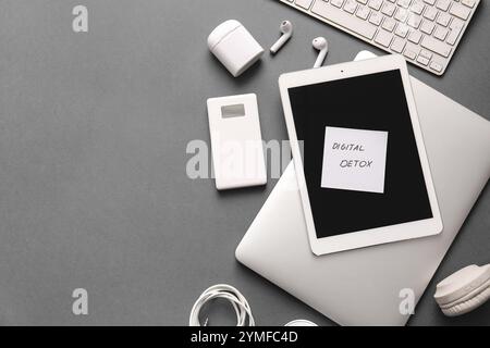 Sticky note with text DIGITAL DETOX and different modern gadgets on dark background Stock Photo