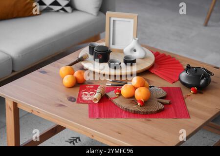 Mandarins with tea and Chinese New Year symbols on table in living room Stock Photo