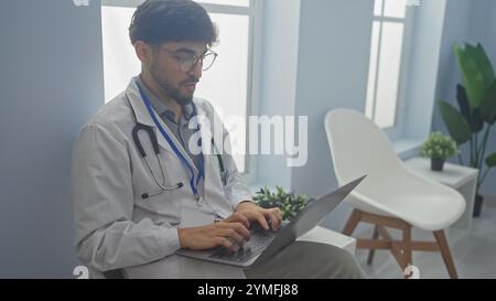 Handsome arab man in glasses and stethoscope using laptop in modern clinic office Stock Photo