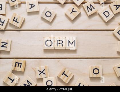 Wooden board with a bunch of wooden letters scattered around it. The letters spell out the word ORM Stock Photo