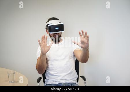 Man using hand gestures to interact with virtual environment while wearing VR headset Stock Photo