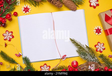 Open notebook with empty blank sheets on yellow background with Christmas decor, top view Stock Photo