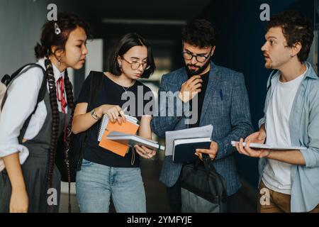 Students engaging in thoughtful discussion with professor between classes Stock Photo