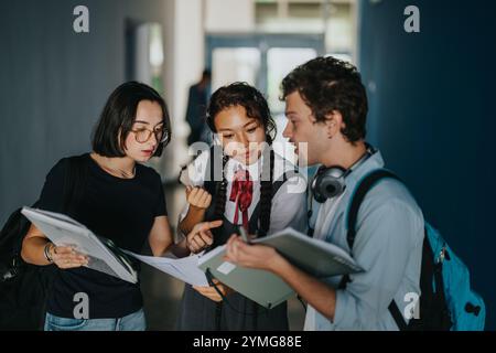 Focused students discussing schoolwork in a busy hallway corridor Stock Photo