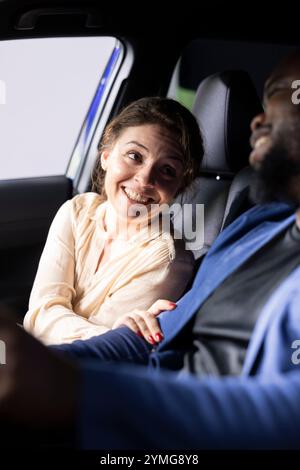 Cheerful customers in car during test drive celebrating closing deal at dealership, proudly looking at each other. Joyous wife and husband satisfied with automobile bought, feeling happy Stock Photo