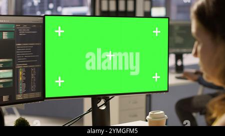 Computer scientist working, doing software debugging using mockup PC, troubleshooting errors. Woman in office fixing coding issues using green screen computer, solving tasks, camera A Stock Photo
