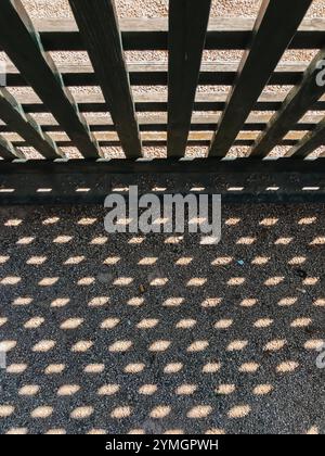 A shadow of a wooden fence on a concrete floor. The shadow is made up of many small dots, creating a pattern that is both interesting and unique Stock Photo
