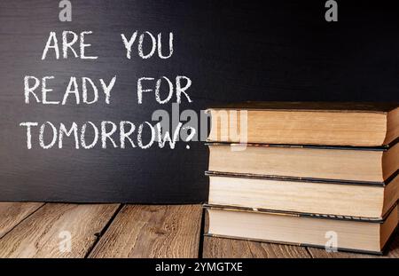 Stack of books with chalk on top that says Are you ready for tomorrow The chalk is written in a way that it looks like it's on top of the books Stock Photo