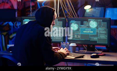 Hacker in hidden base successfully getting past anti tamper measures implemented by companies to protect products. Cracker pirating software and video game releases, camera B Stock Photo