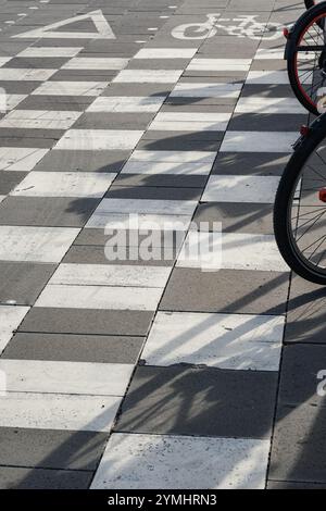 Double cycle lane with road markings near a pedestrian crossing giving access to a bicycle parking area. Close-up view, vertical composition. Stock Photo