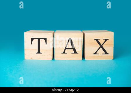 Three wooden blocks with the word tax written on them. The blocks are arranged in a way that they spell out the word tax. Concept of importance and se Stock Photo