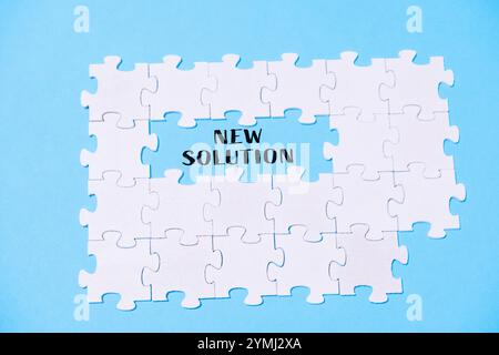 Puzzle with the word new solution written in the middle. The puzzle pieces are scattered around the word, creating a sense of disarray and confusion Stock Photo