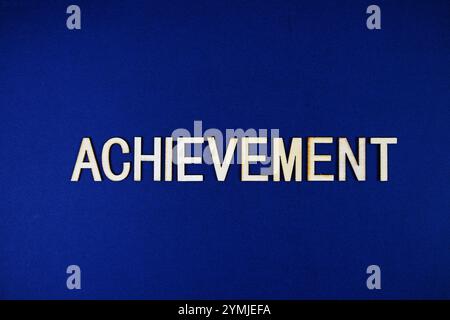 Achievement alphabet letters with gears element on navy blue background Stock Photo