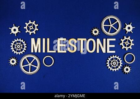 Milestone alphabet letters with gears element on navy blue background Stock Photo