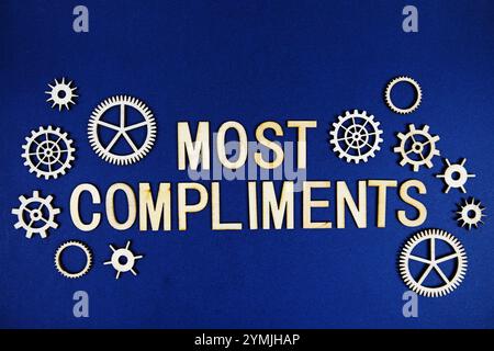 Most Compliments alphabet letters with gears element on navy blue background Stock Photo