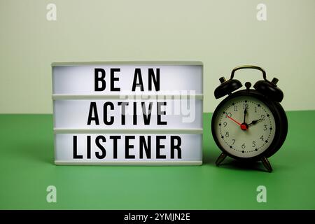 Be An Active Listener text on LED lightbox with alarm clock on green background Stock Photo