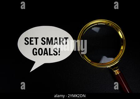 Set smart goals text on speech bluble with magnifying glass top view on black background Stock Photo