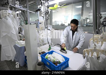 SUQIAN, CHINA - NOVEMBER 22, 2024 - A worker produces shirts on an assembly line at a smart production workshop at a garment factory in Suqian, Jiangs Stock Photo