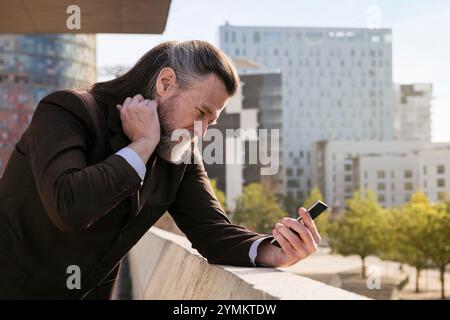 concerned mature man in suit using mobile phone Stock Photo