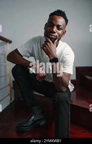 Portrait of Black Man Sitting on Wooden Staircase Stock Photo