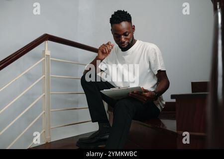 Man Reviewing Documents While Sitting on Stairs Stock Photo