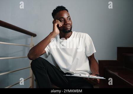 African American Man Sitting Thoughtfully Holding Tablet Stock Photo