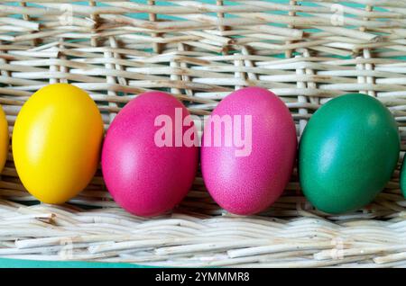 close up of four easter eggs colored in a straw basket Stock Photo