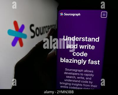 In this photo illustration, a person is holding a cellphone with the website of US code intelligence company Sourcegraph Inc. in front of logo. (Photo by Timon Schneider / SOPA Images/Sipa USA) *** Strictly for editorial news purposes only *** Stock Photo