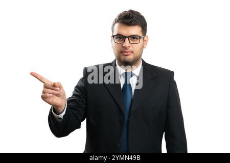 Serious entrepreneur man wearing casual corporate office clothing suit and tie pointing index finger at blank copyspace for advertising isolated on wh Stock Photo