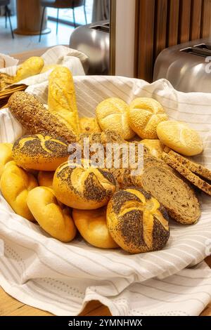 Assorted bread in wicker basket, baguettes and buns on a counter, hotel breakfast concept Stock Photo
