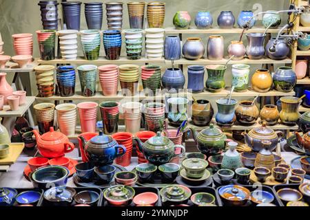 A counter with beautiful ceramic teapots and cups of various shapes and colors. Stock Photo