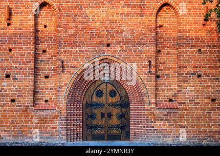 Large oak doors covered with metal strips from an old Catholic church. Red brickwork. Stock Photo