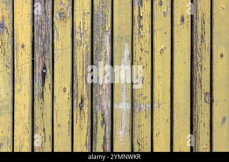 Old door boards with peeling yellow paint nailed with rusty nails. Stock Photo