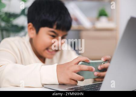 Getting serious asian boy using smartphone for playing mobile game Inside the house. Smartphone gaming online. Stock Photo